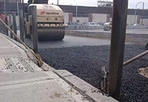 Paving vehicle flattening a stretch of road