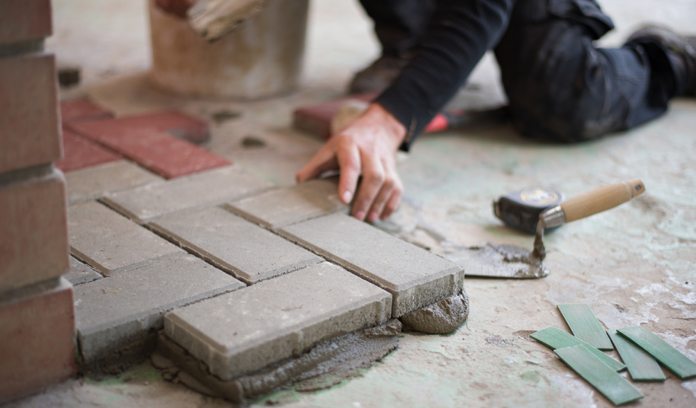 builder laying paving stones in ground